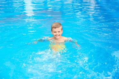 Little boy in swimming pool on sunny day