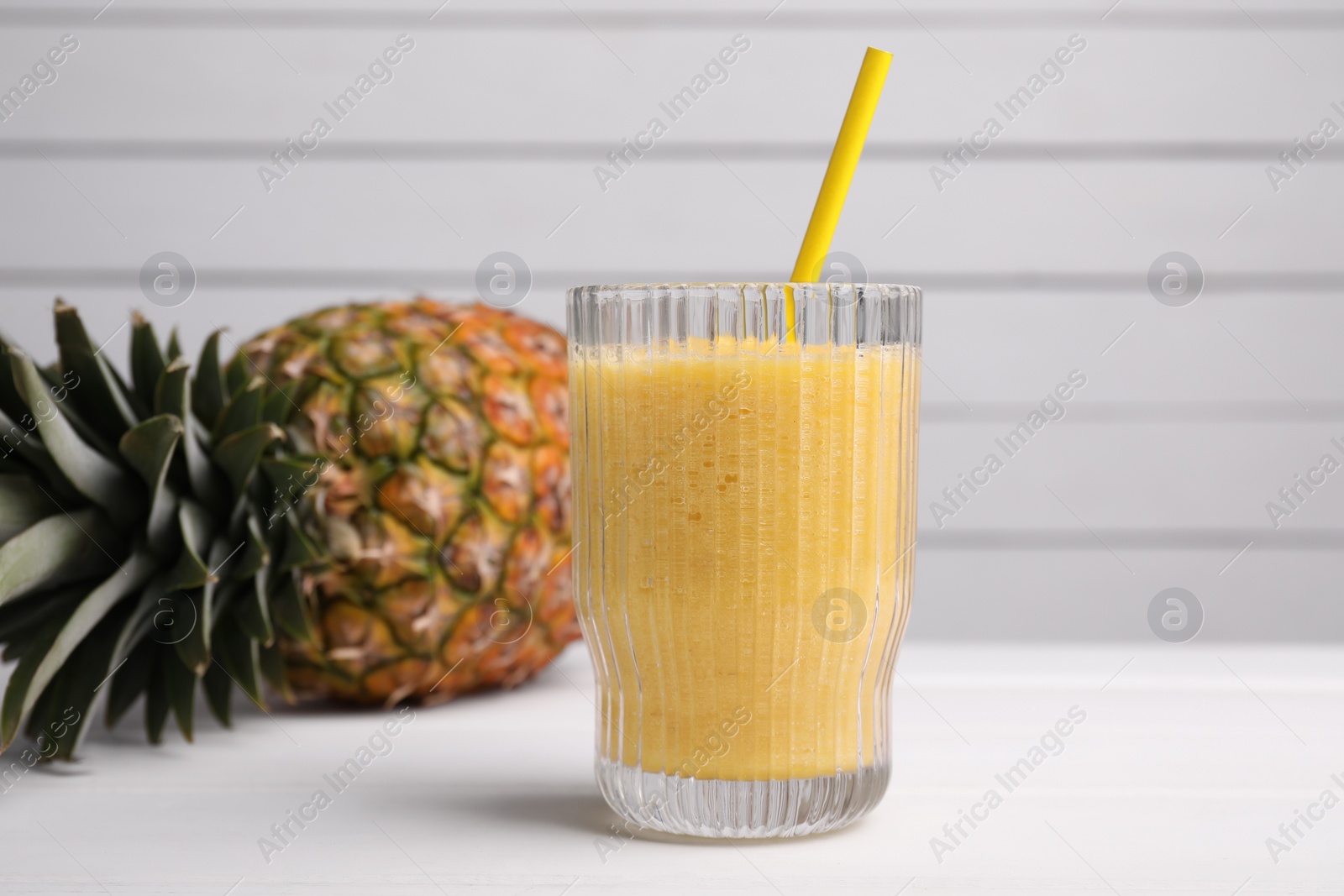 Photo of Tasty pineapple smoothie and fresh fruit on white table