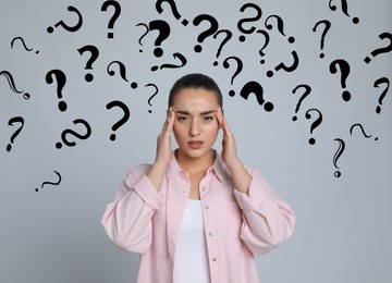 Image of Amnesia. Confused young woman and question marks on light grey background