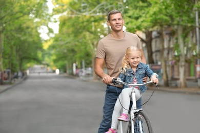 Man and his little daughter with bicycle on street