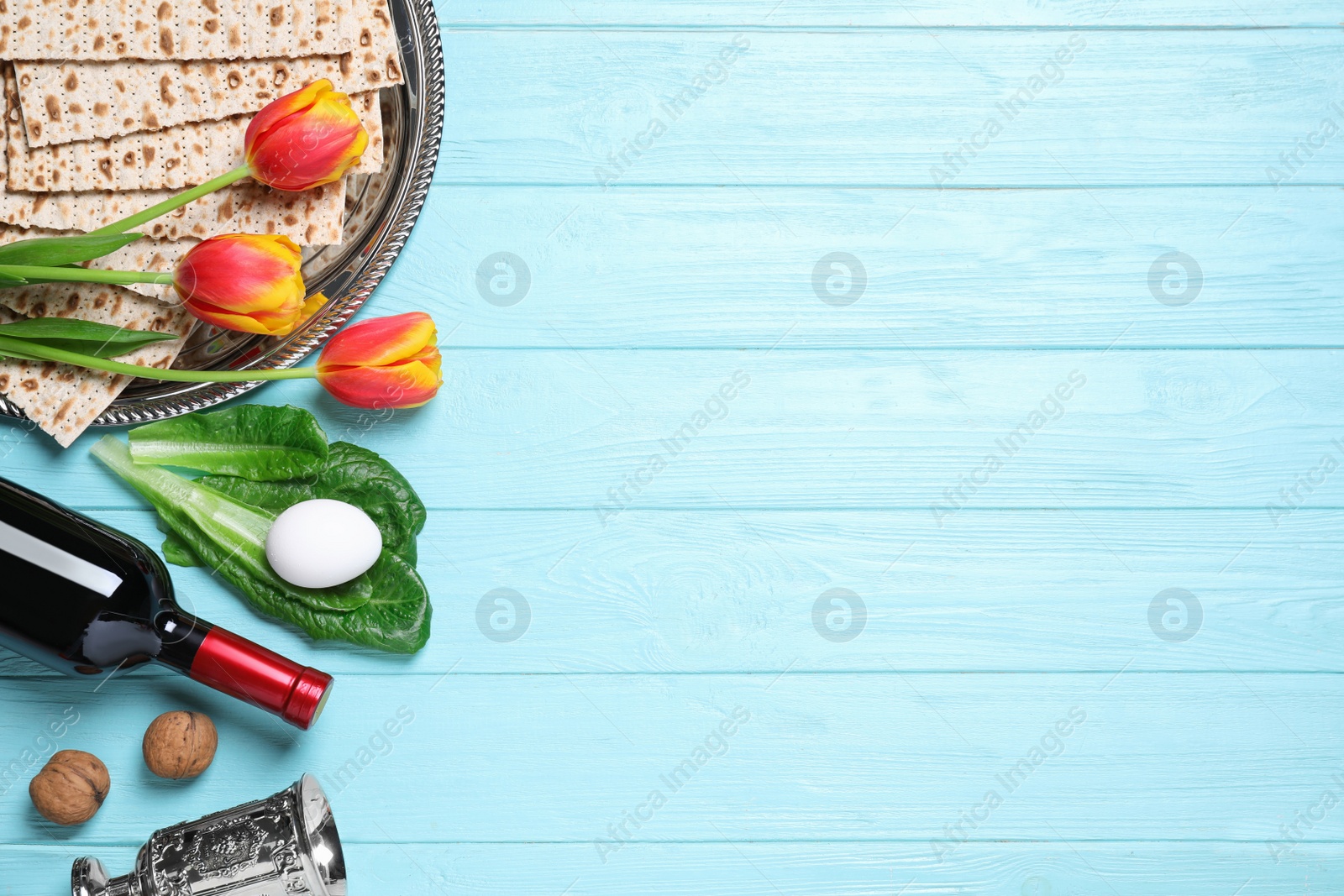 Photo of Flat lay composition with symbolic Pesach (Passover Seder) items on light blue wooden table, space for text