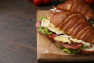 Photo of Tasty croissant with brie cheese and bacon on wooden table, closeup. Space for text