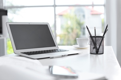Photo of Modern laptop and supplies on table in office