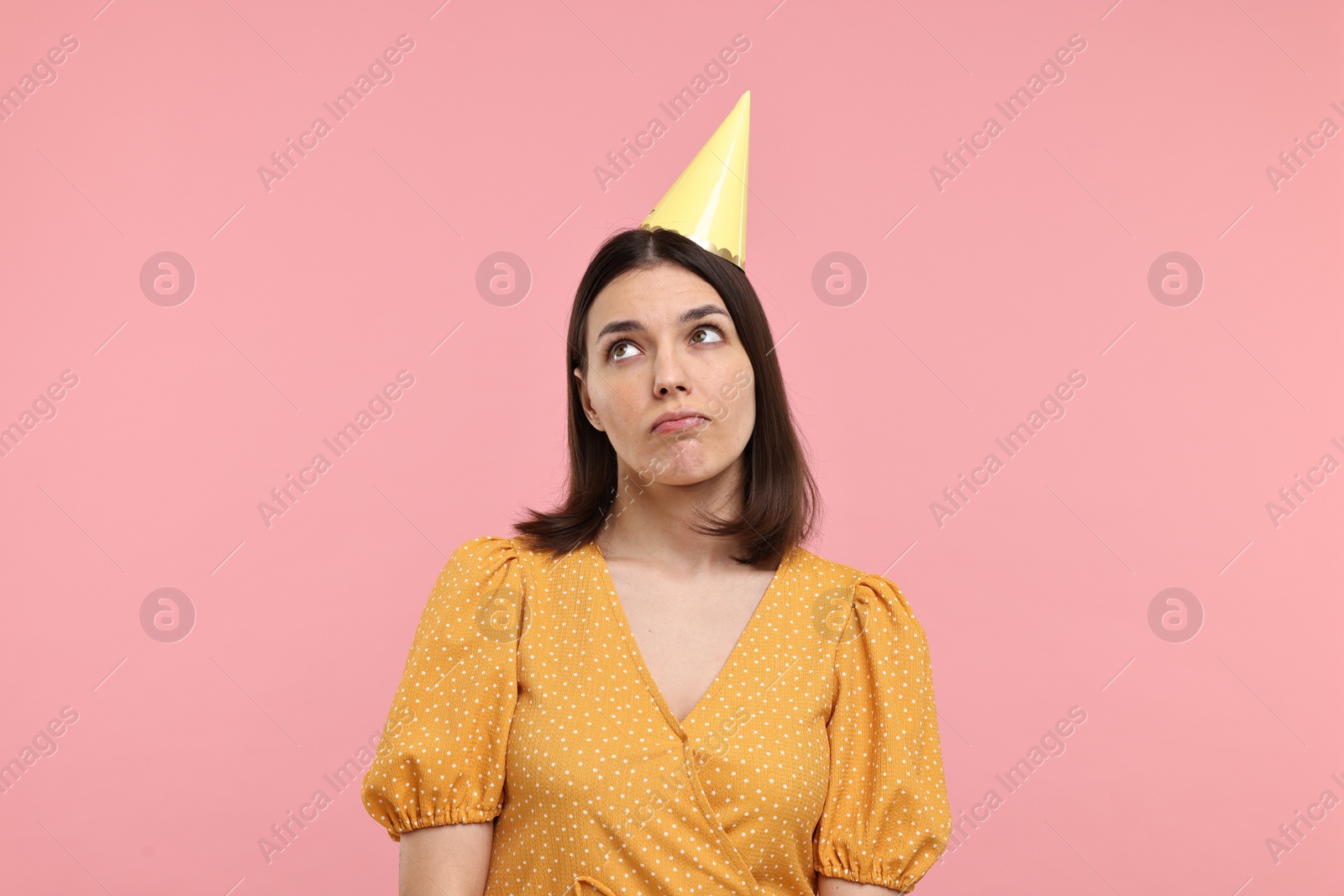 Photo of Sad young woman in party hat on pink background