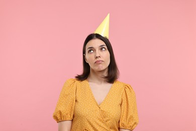 Photo of Sad young woman in party hat on pink background