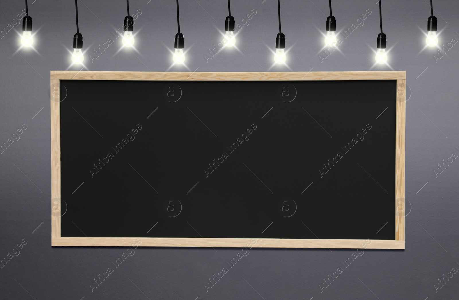 Image of Glowing light bulbs and blackboard hanging on grey wall