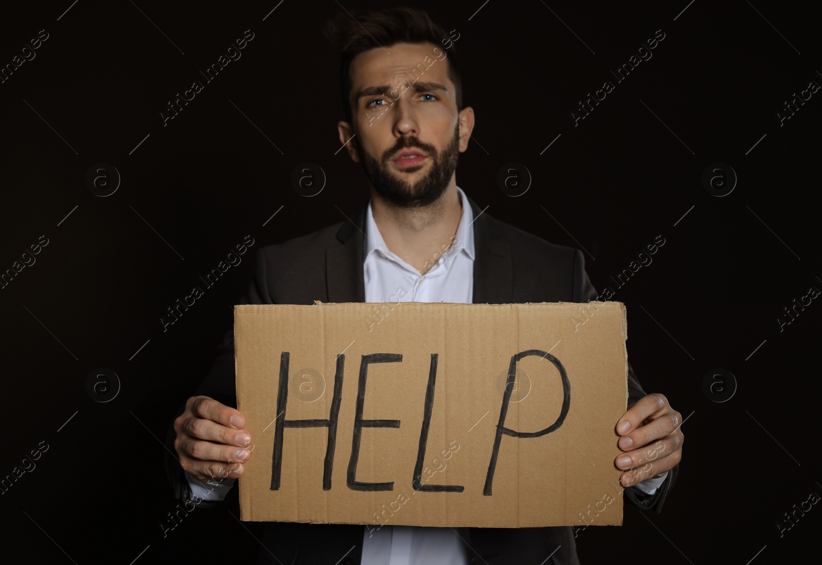 Photo of Unhappy man with HELP sign on dark background
