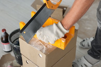 Worker cutting decorative bricks with saw indoors, closeup