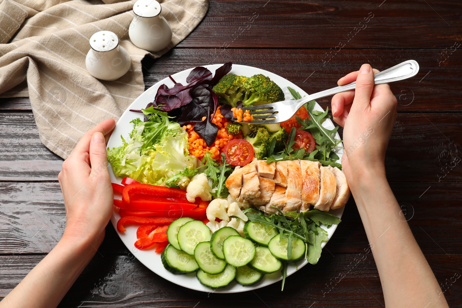 Photo of Balanced diet and healthy foods. Woman eating dinner at wooden table, above view