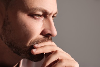 Photo of Upset man crying on beige background, closeup with space for text. Loneliness concept