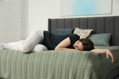 Sad young woman lying on bed at home