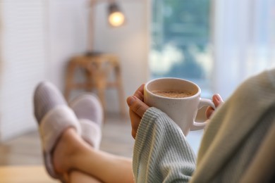 Woman with cup of aromatic coffee relaxing at home, closeup