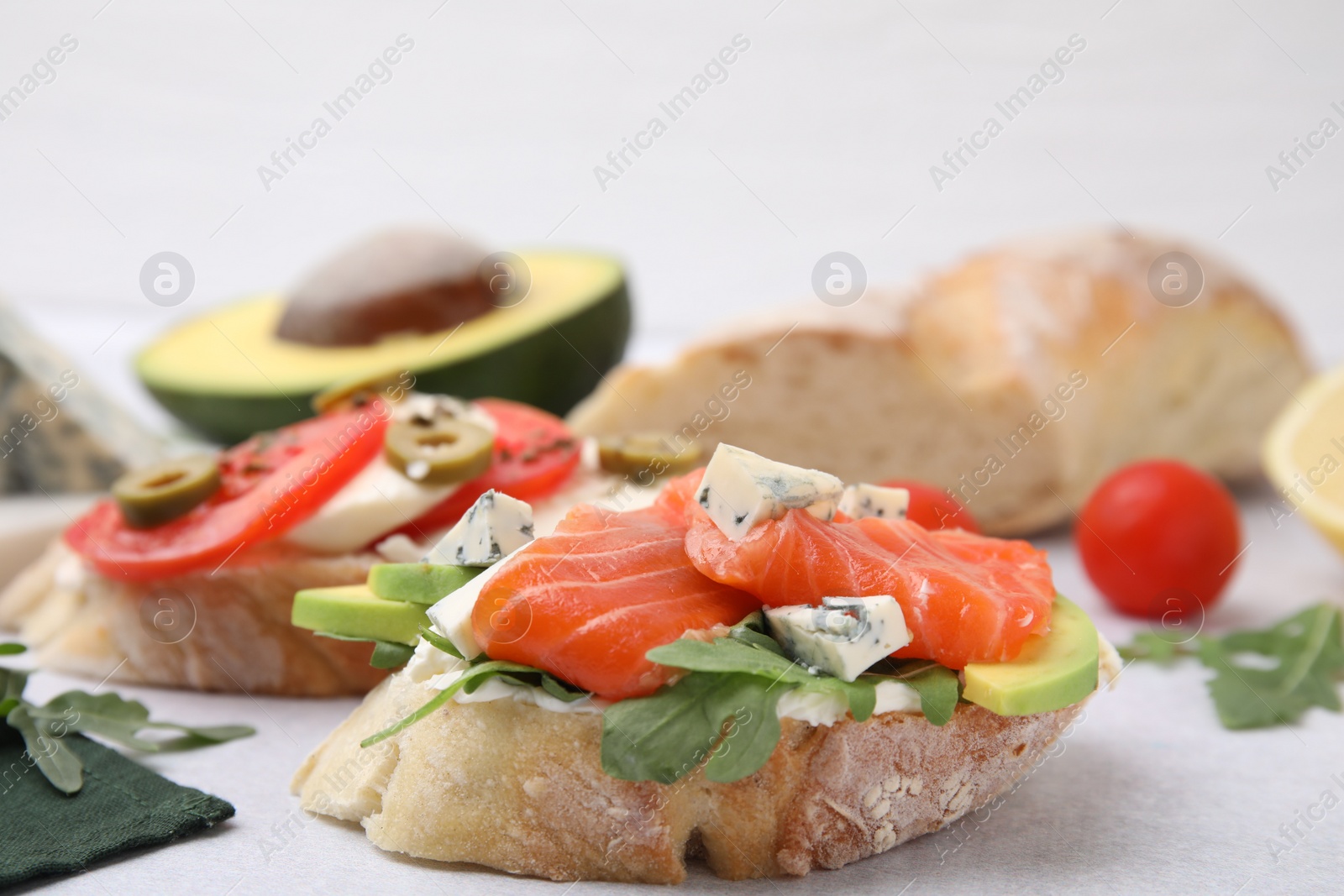 Photo of Different tasty bruschettas and ingredients on light grey textured table, closeup