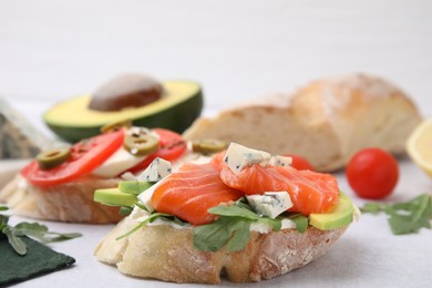 Photo of Different tasty bruschettas and ingredients on light grey textured table, closeup