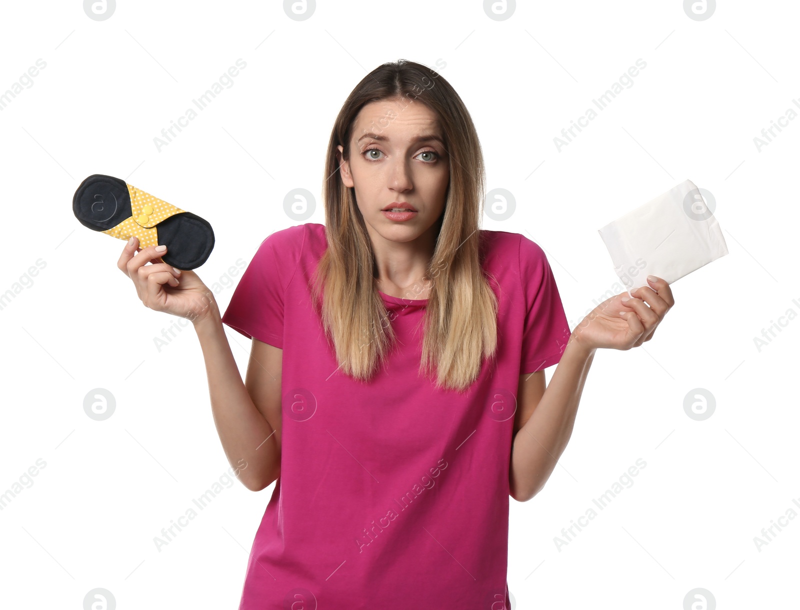 Photo of Confused young woman with disposable and reusable cloth menstrual pads on white background