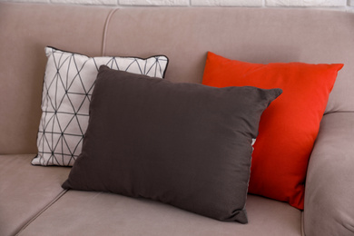Photo of Colorful soft pillows on modern sofa in room