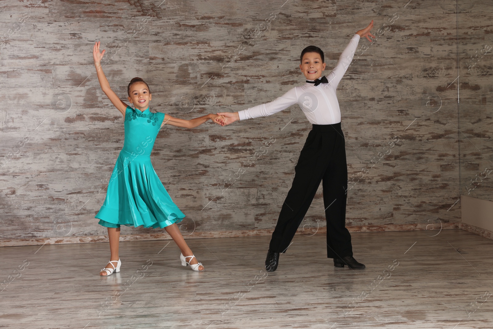 Photo of Beautifully dressed couple of kids dancing together in studio