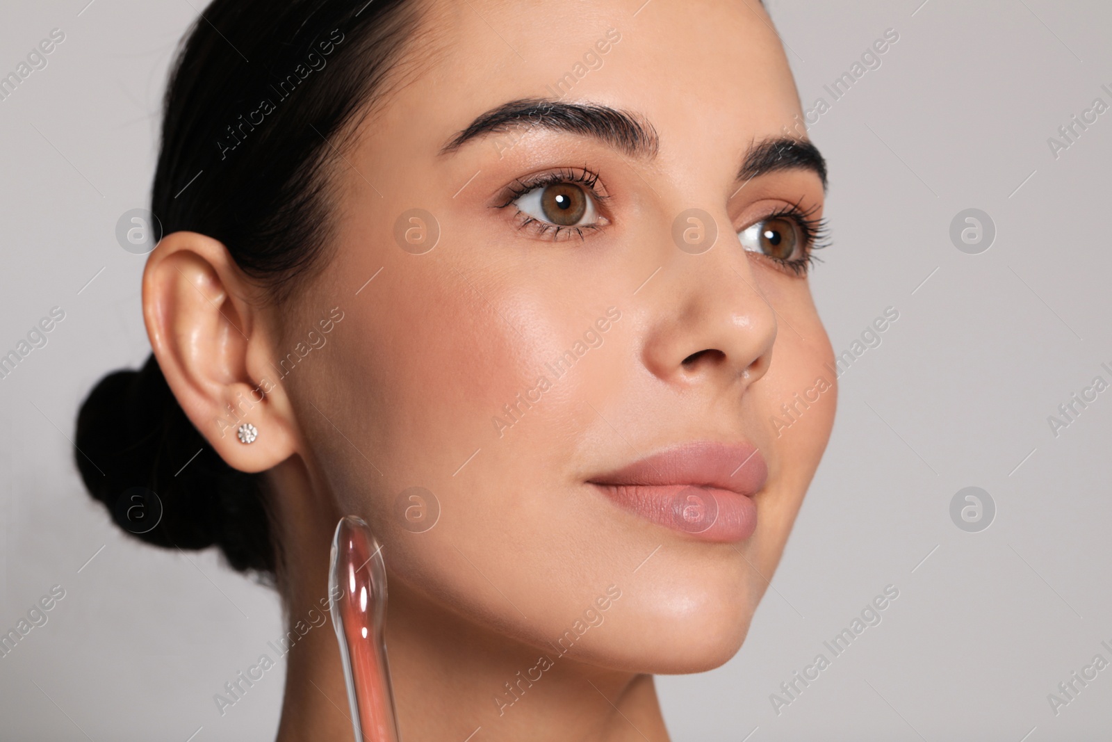 Photo of Woman using high frequency darsonval device on grey background, closeup