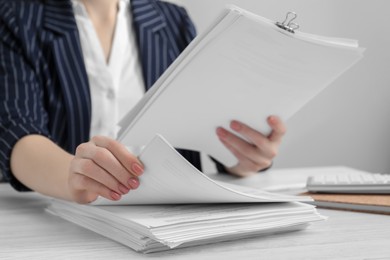 Photo of Woman reading documents at white wooden table in office, closeup