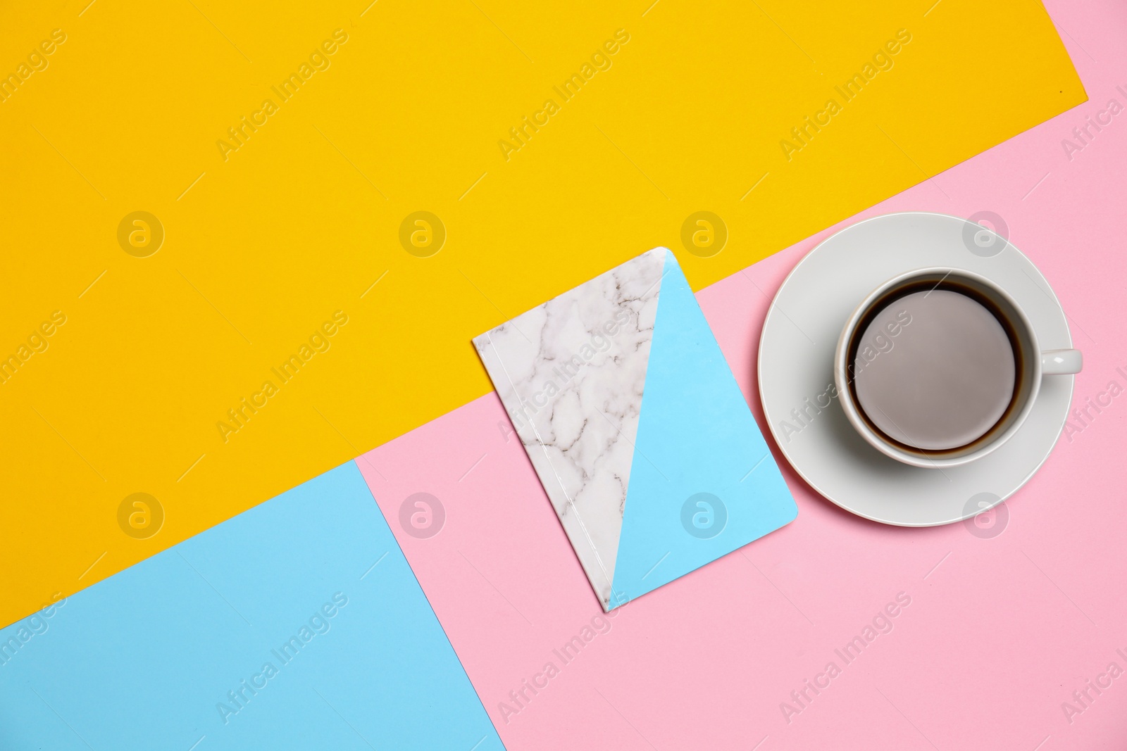 Photo of Notebook and cup of coffee on color background, top view. Space for text