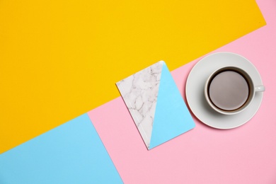 Photo of Notebook and cup of coffee on color background, top view. Space for text