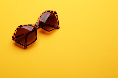 Stylish sunglasses on yellow background, space for text. Fashionable accessory