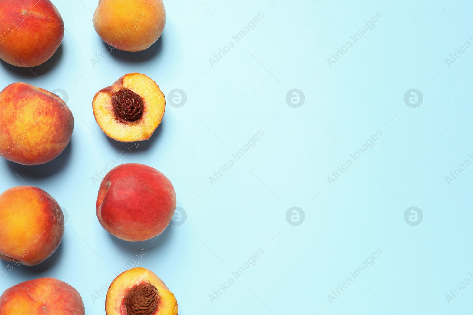 Photo of Delicious juicy peaches on light blue background, flat lay. Space for text