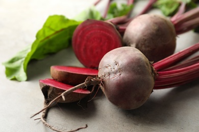 Cut and whole raw beets on light grey table, closeup