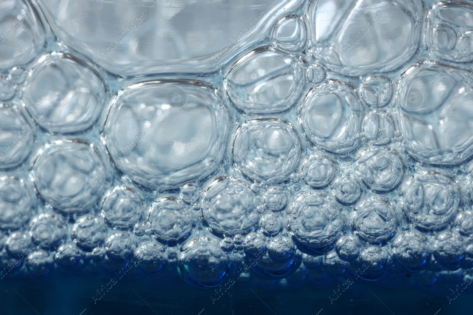 Photo of Texture of glass cleaning liquid with bubbles, macro view