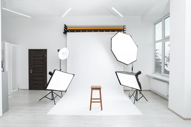 Interior of modern photo studio with bar stool and professional lighting equipment