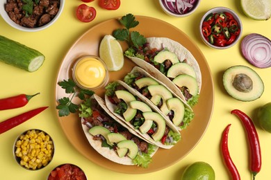 Photo of Flat lay composition with delicious tacos on yellow table