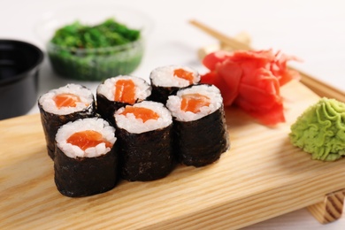 Photo of Tasty sushi rolls on wooden board. Food delivery