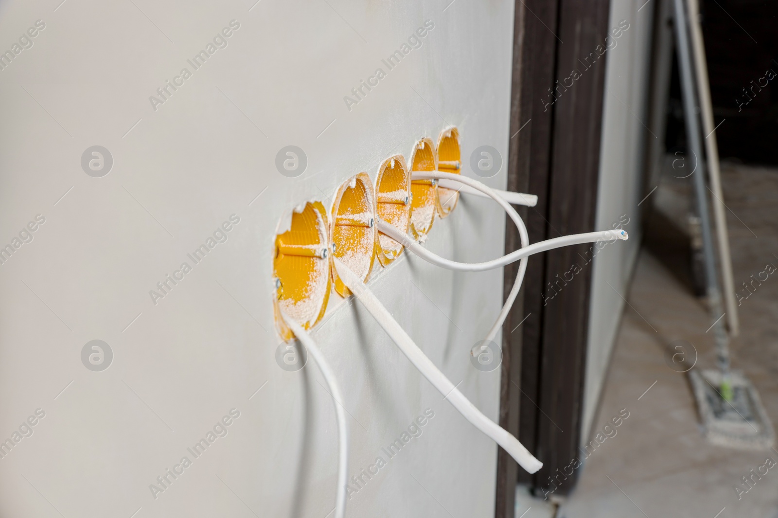 Photo of Holes for socket in white wall with cables indoors. Installation of electrical wiring