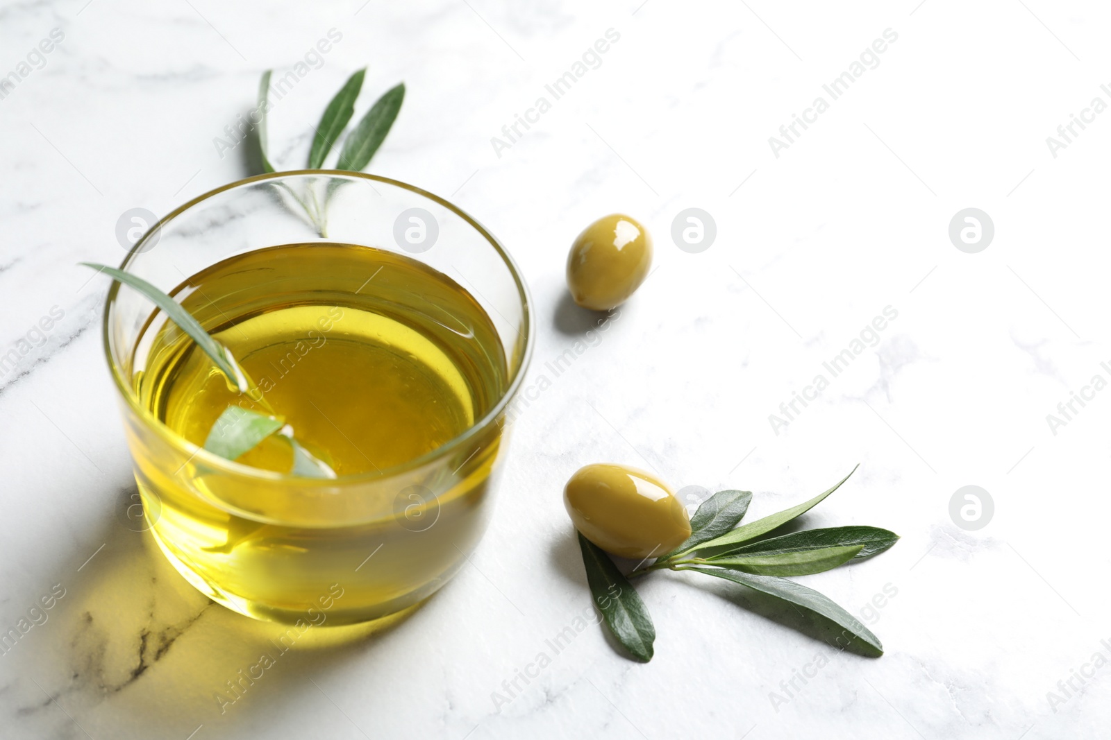 Photo of Glass with fresh olive oil on table