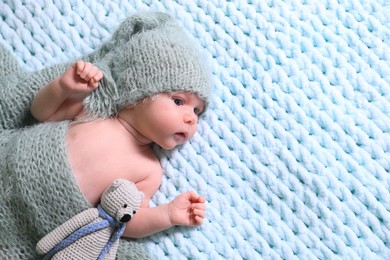 Photo of Cute newborn baby with pacifier and crochet toy on light blue blanket, top view. Space for text