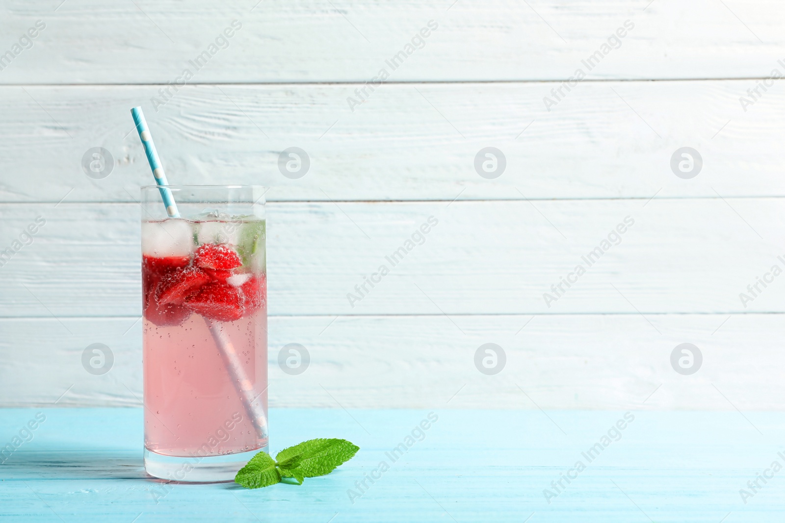 Photo of Natural lemonade with strawberries in glass on wooden table