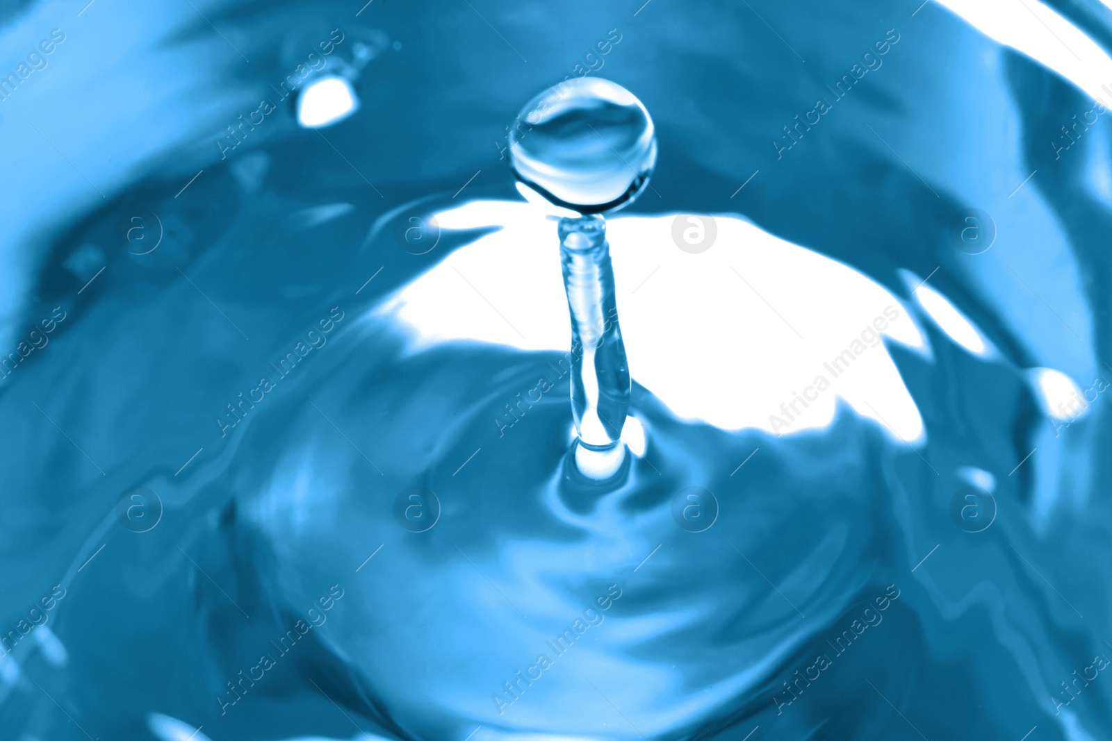 Photo of Splash of clear water with drop on blue background, closeup