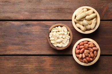 Fresh peanuts in bowls on wooden table, top view. Space for text