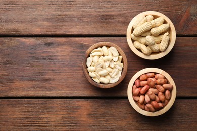 Photo of Fresh peanuts in bowls on wooden table, top view. Space for text