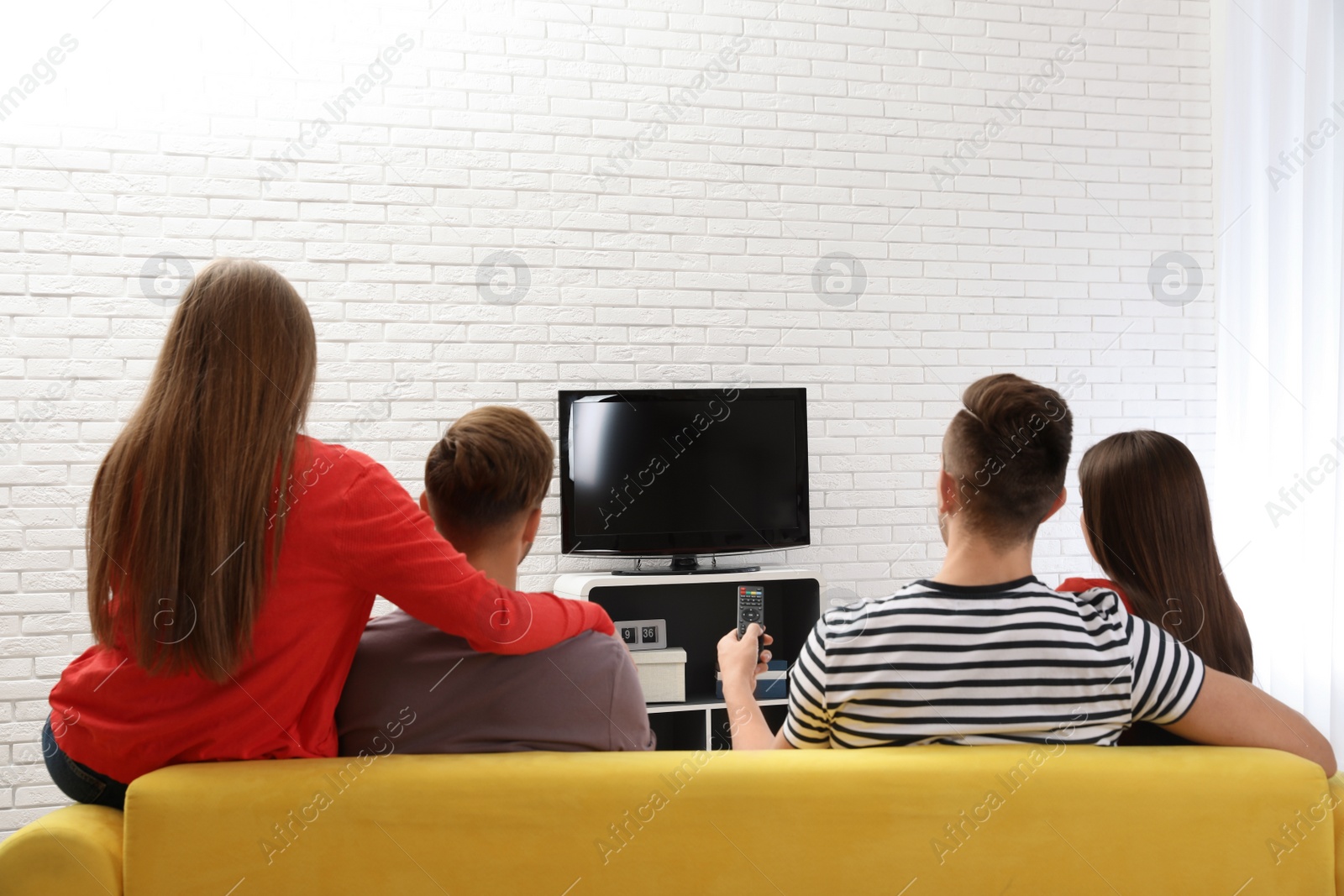 Photo of Group of people watching TV together on sofa in living room. Space for text