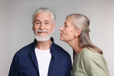 Photo of Senior woman kissing her beloved man on light grey background