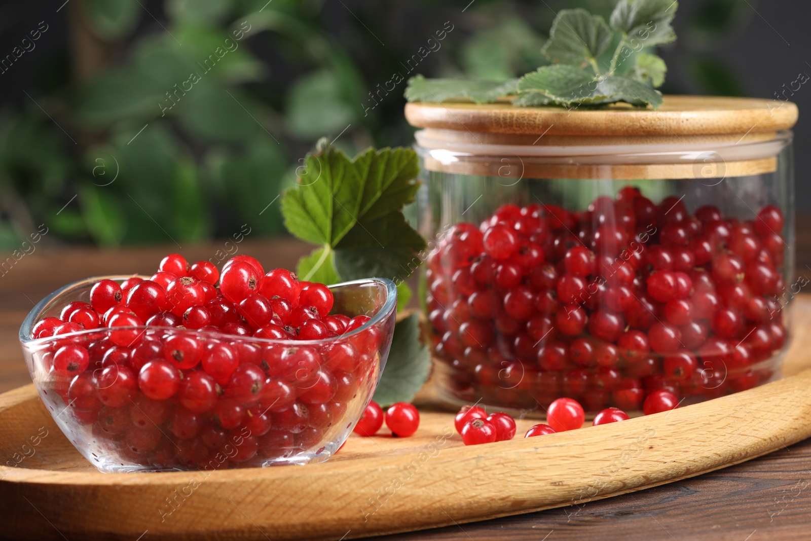 Photo of Ripe red currants and leaves on wooden table, closeup