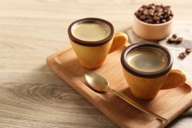 Delicious biscuit cups with espresso and spoon on wooden table. Space for text