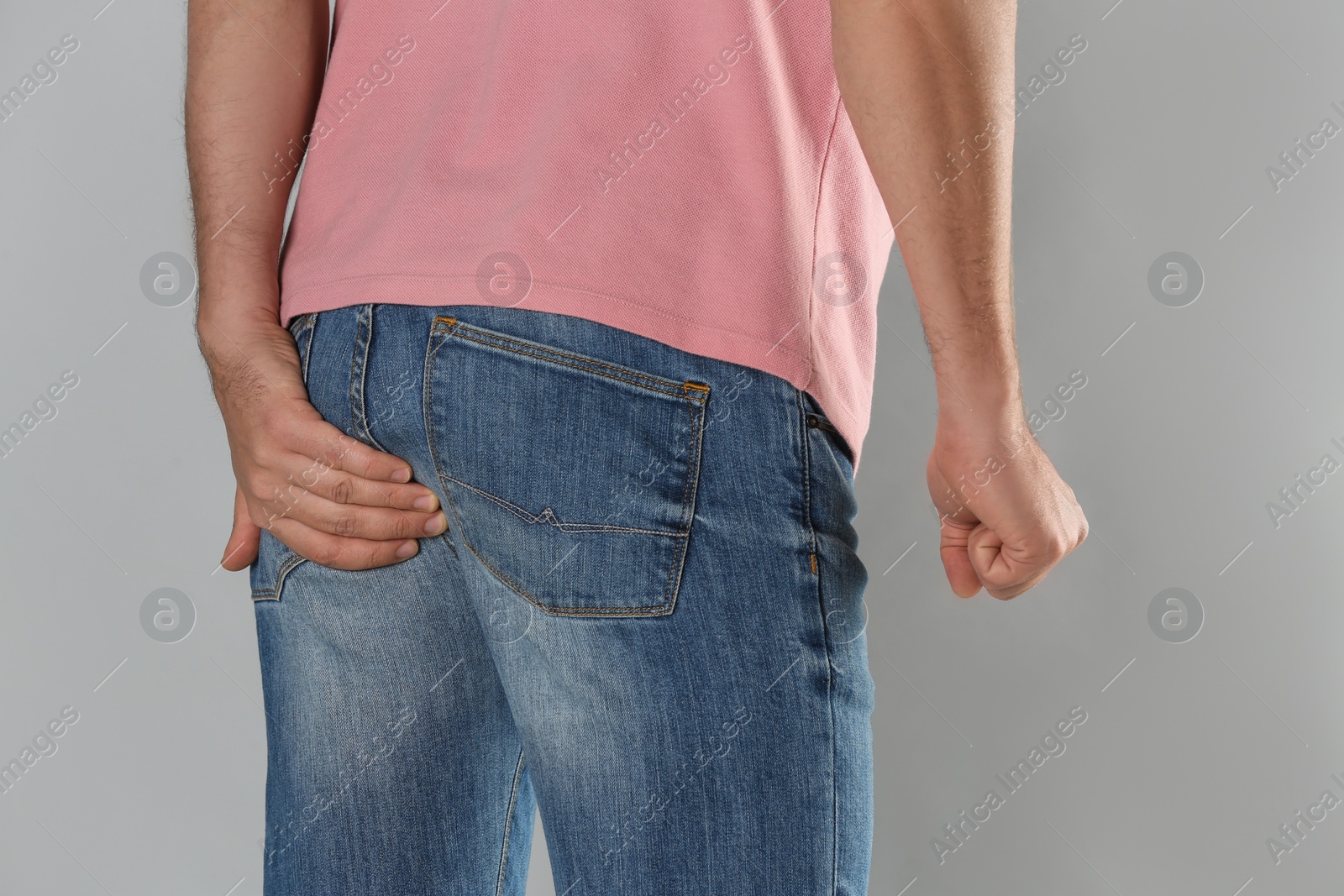 Photo of Man suffering from hemorrhoid on light grey background, closeup