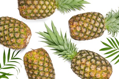 Photo of Whole ripe pineapples and green leaves on white background, flat lay