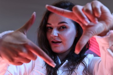 Portrait of beautiful young woman on color background with neon lights