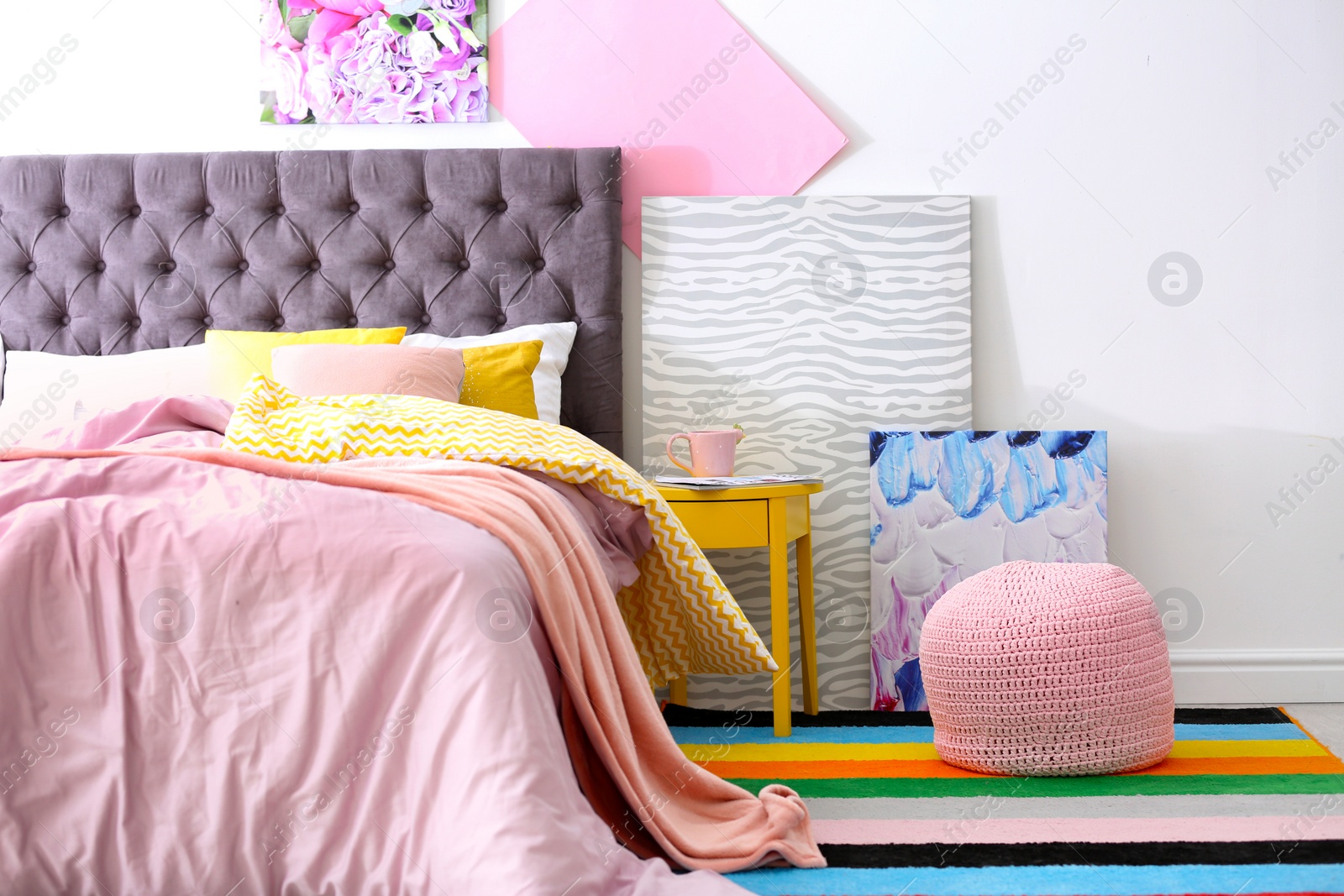 Photo of Stylish room interior with comfortable bed and rainbow carpet