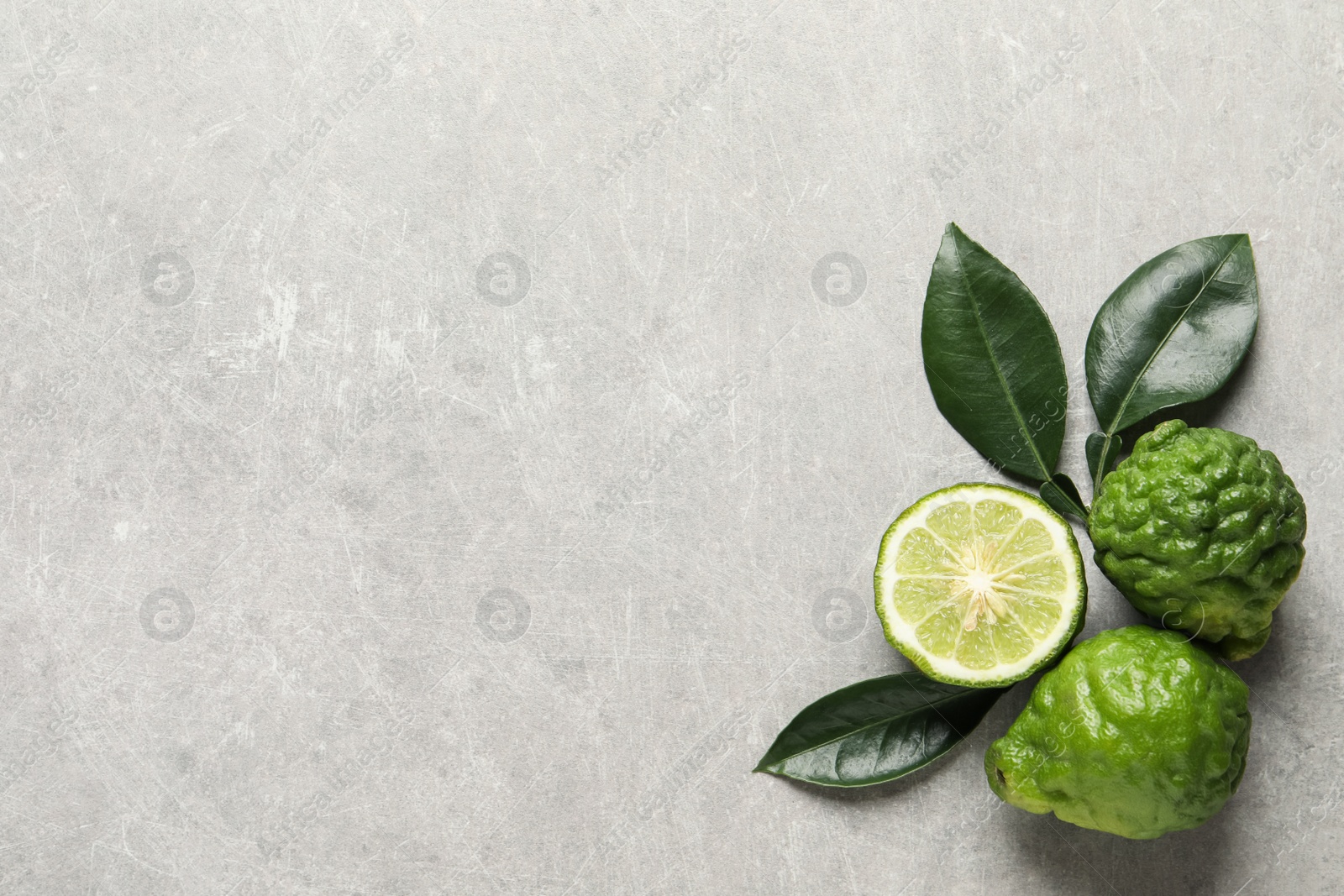 Photo of Fresh ripe bergamot fruits and leaves on light grey table, flat lay. Space for text