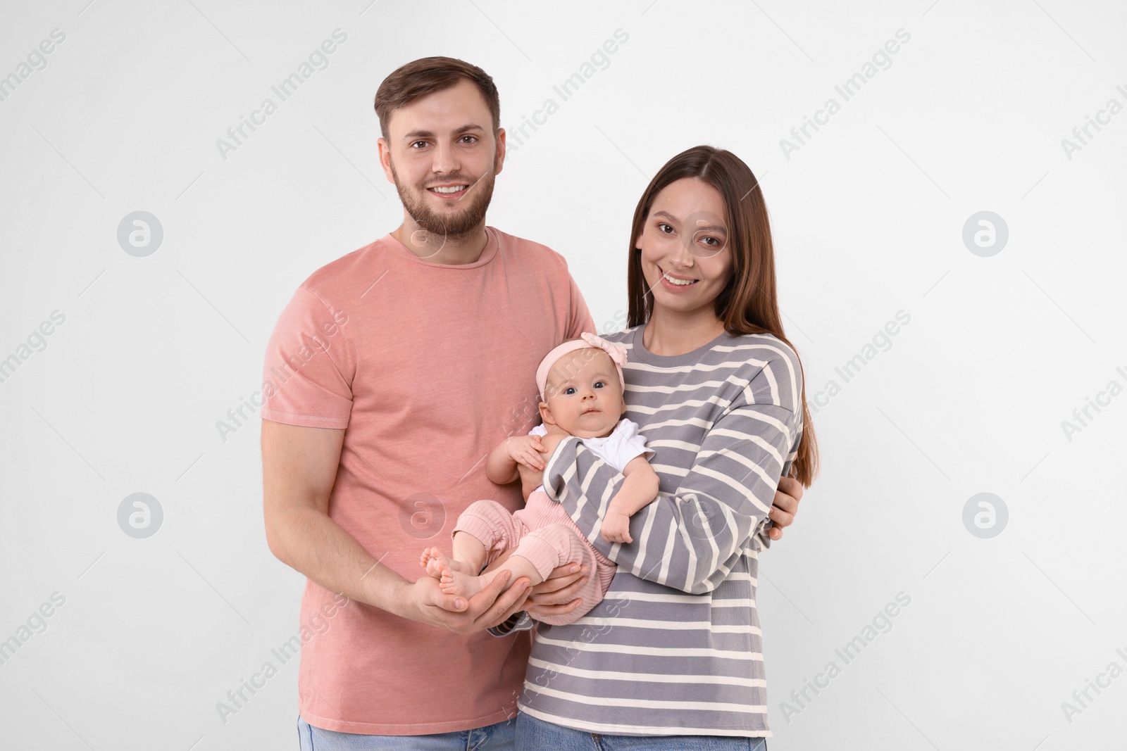 Photo of Happy family. Parents with their cute baby on light background