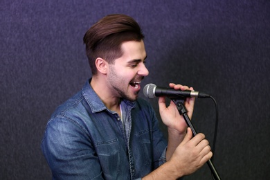 Photo of Young singer with microphone recording song in studio